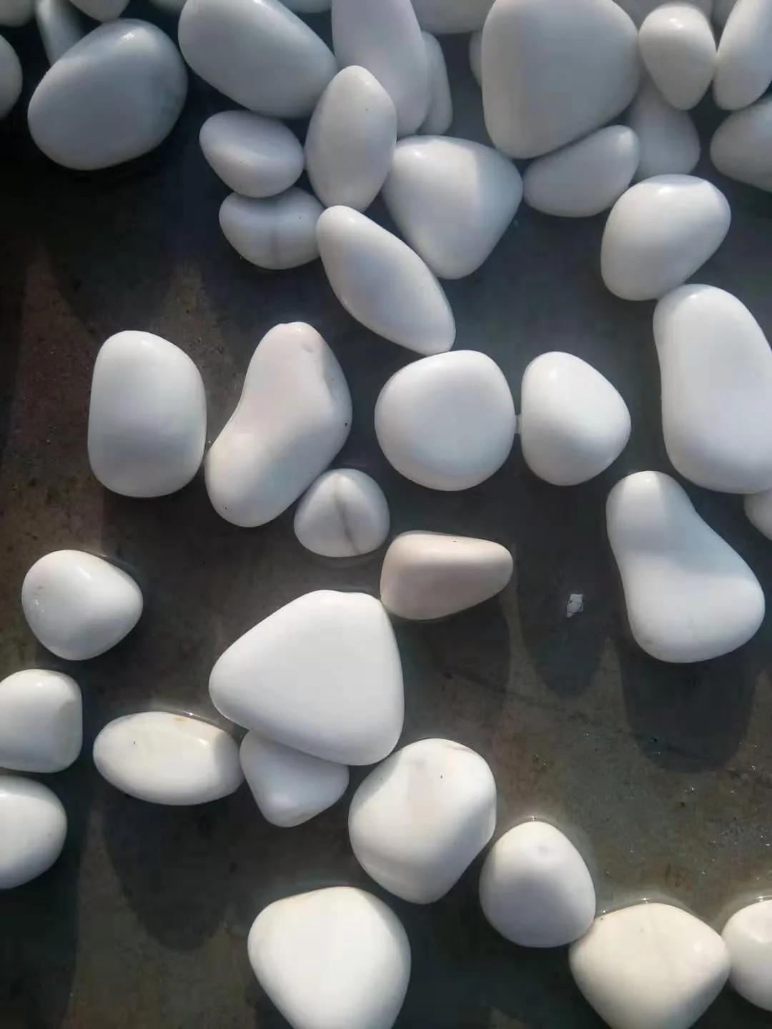 Smooth white decorative pebbles after stone tumbling and polishing